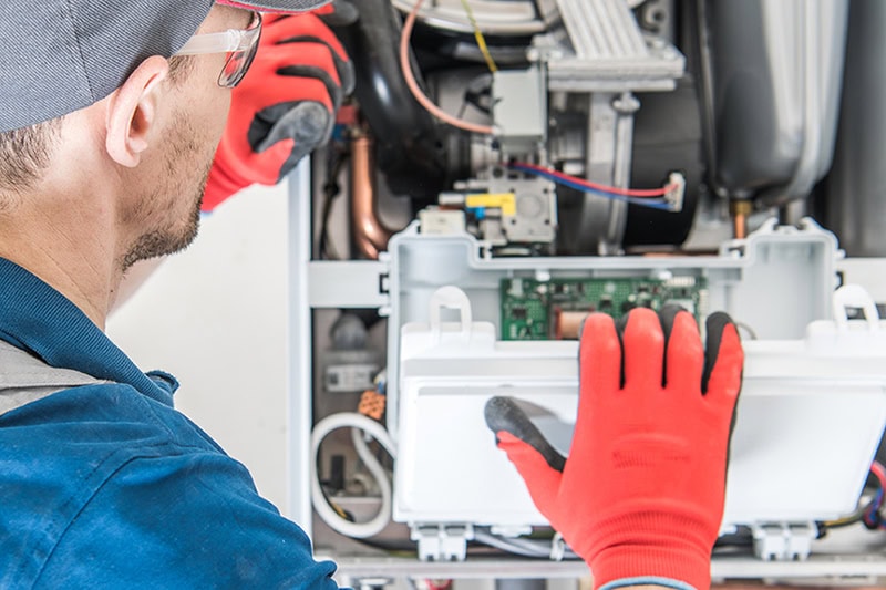 Schedule Your Annual Furnace Inspection Now. Close up photo of a technician inspecting an HVAC Unit.