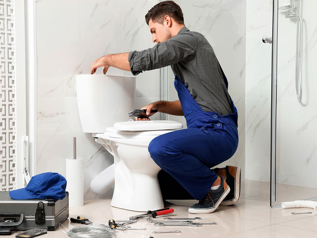 Plumber fixing noisy toilet plumbing