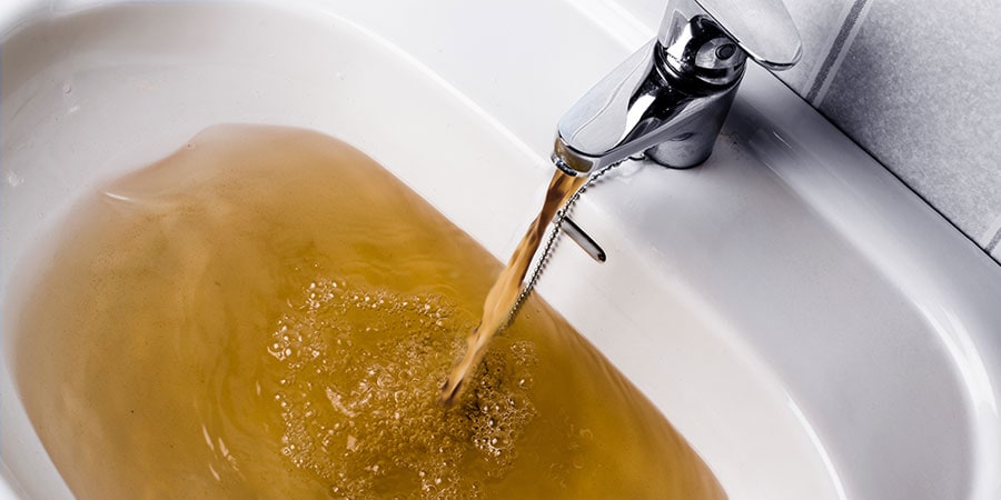 Brown water coming out of bathroom sink faucet representing info on what to do.